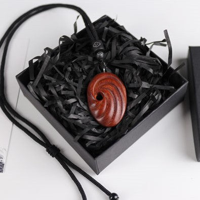 Wooden pendant necklace in a black box with black tissue paper on a white background