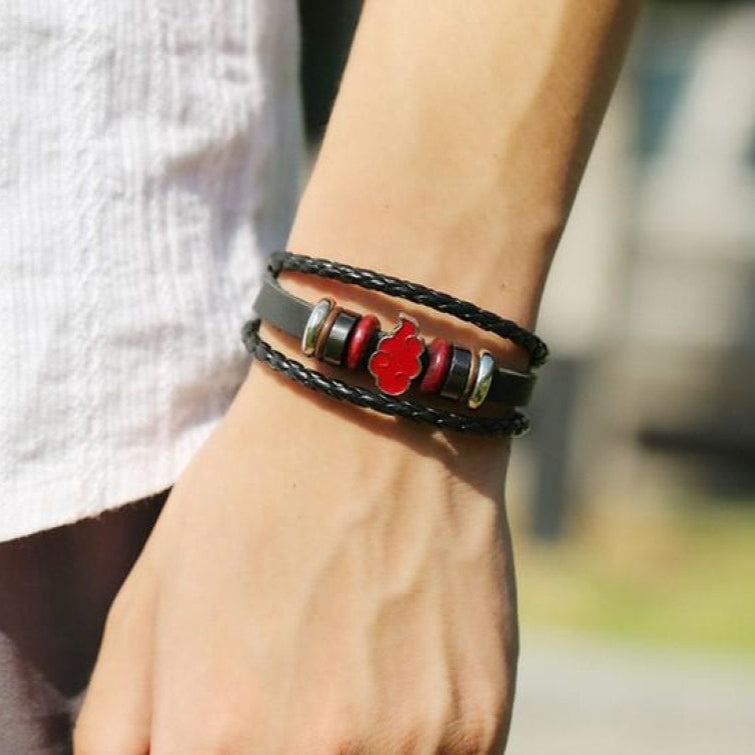Close-up of a wrist wearing a braided bracelet with a red apple charm, blurred background