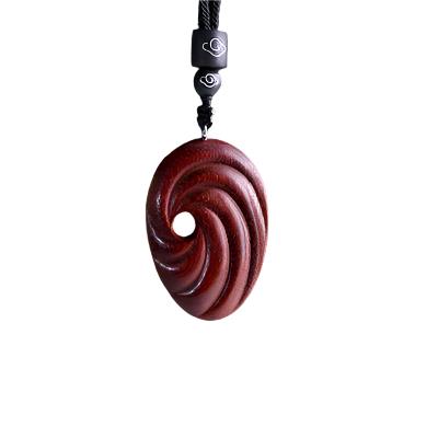 Wooden spiral pendant on a black cord with a visible brand logo against a white background