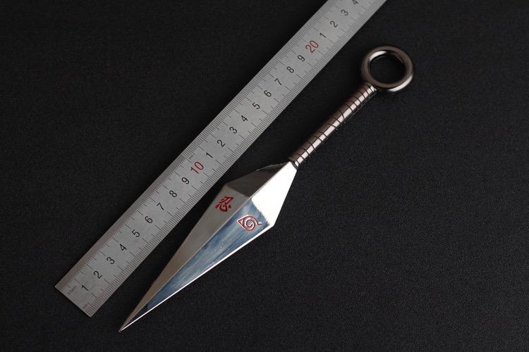 Metallic knife with a decorative handle next to a ruler on a black background