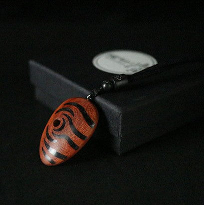 Wooden pendant with black spiral design on a dark background