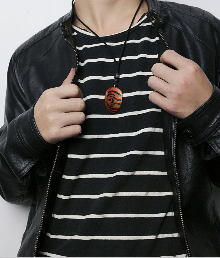 Person wearing a black leather jacket and a black and white striped shirt, with a necklace featuring a wooden pendant.