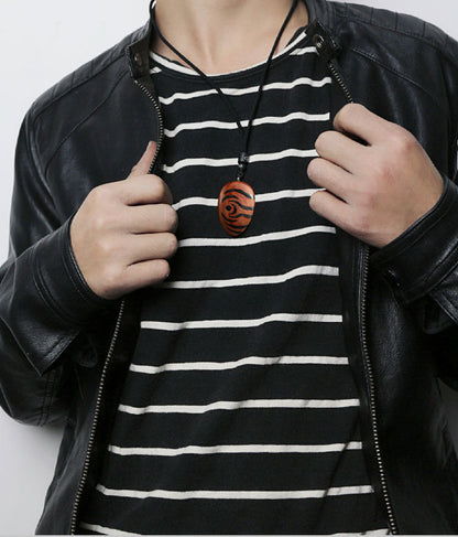 Person wearing a black leather jacket and a black and white striped shirt, with a necklace featuring a wooden pendant.